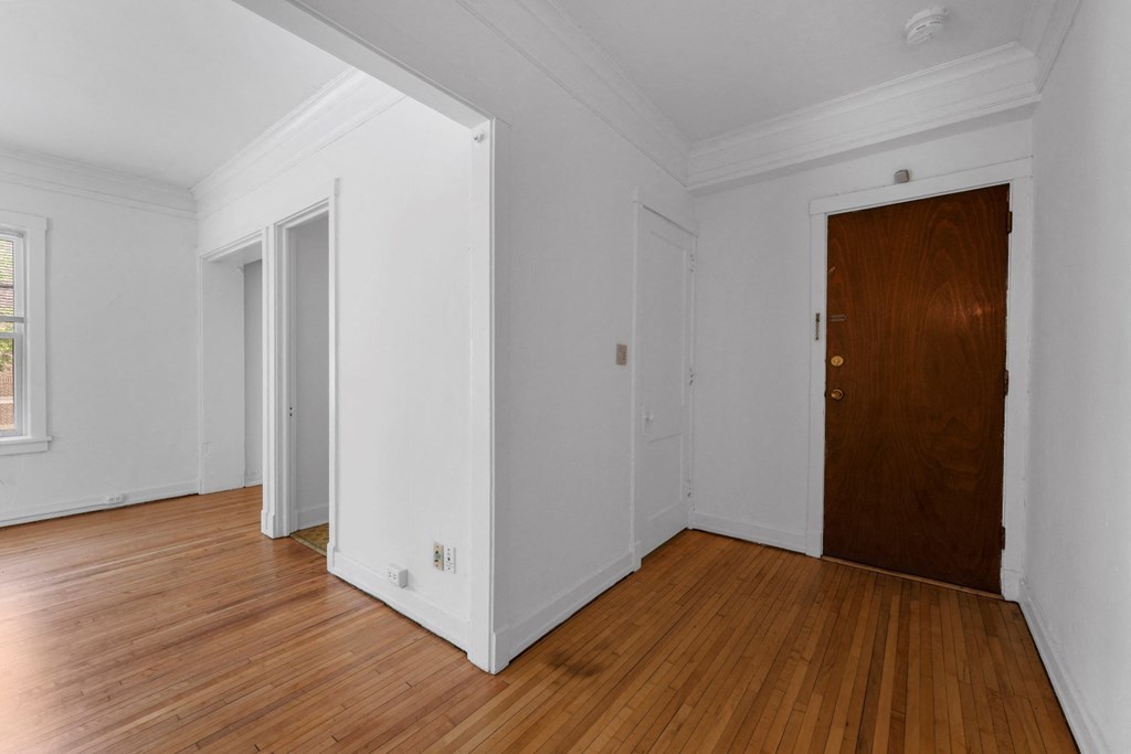a bedroom with hardwood floors and white walls