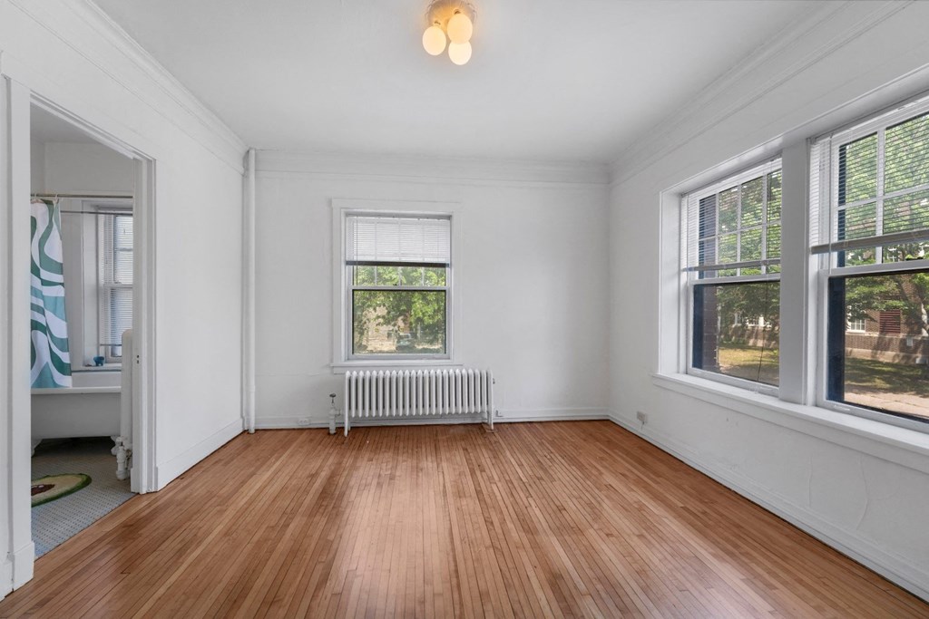 a bedroom with hardwood floors and white walls