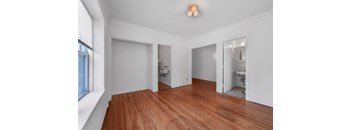 a bedroom with a hardwood floor and white walls
