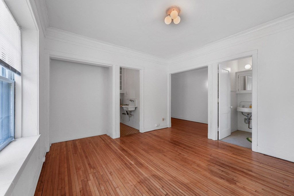 a bedroom with a hardwood floor and white walls