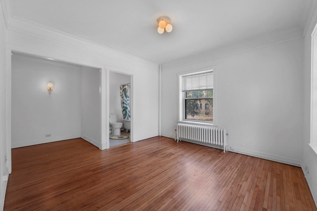 a bedroom with hardwood floors and a large window