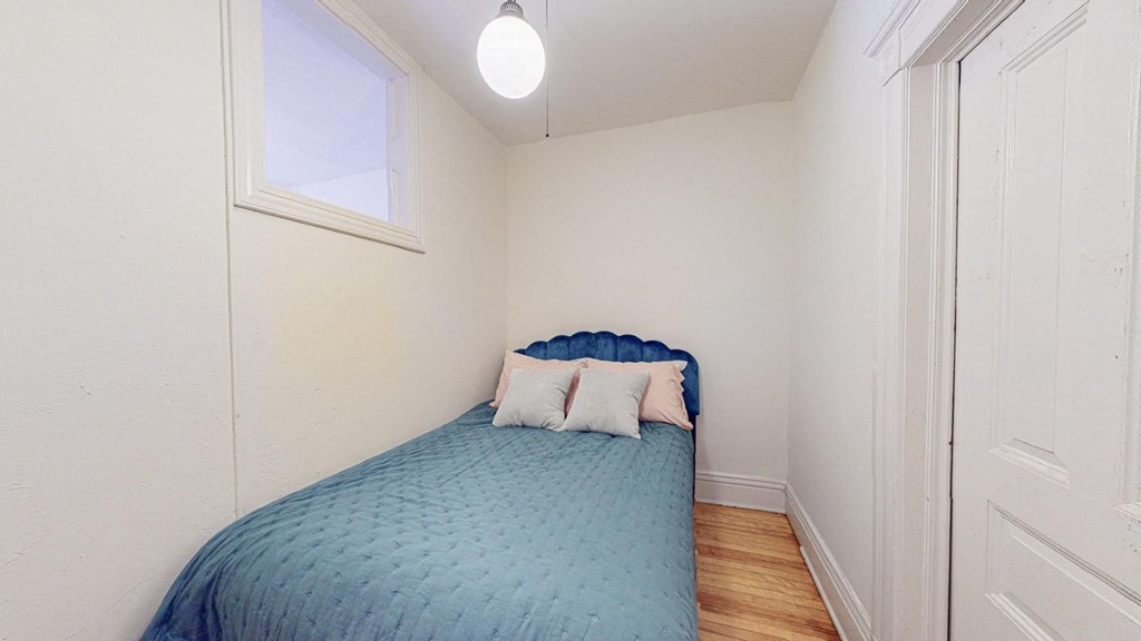 A small bedroom with a bed and a window.