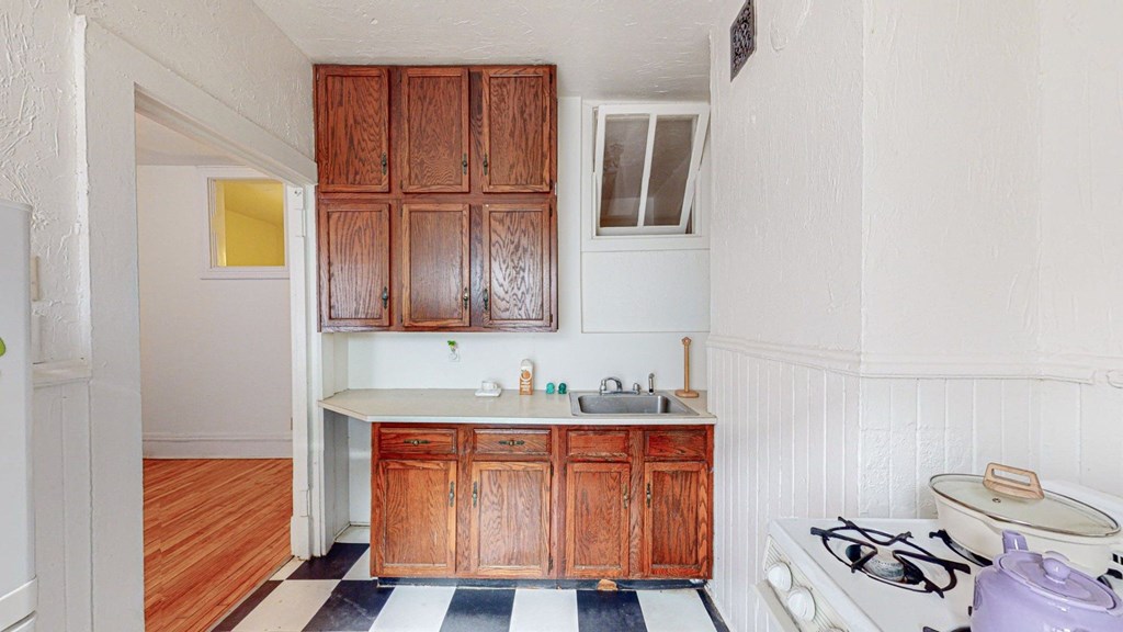 A kitchen with wooden cabinets and a black and white checkered floor.