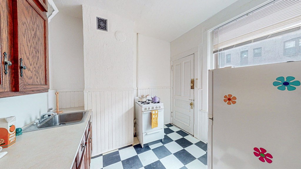 A kitchen with a checkered floor and a refrigerator with flower magnets.