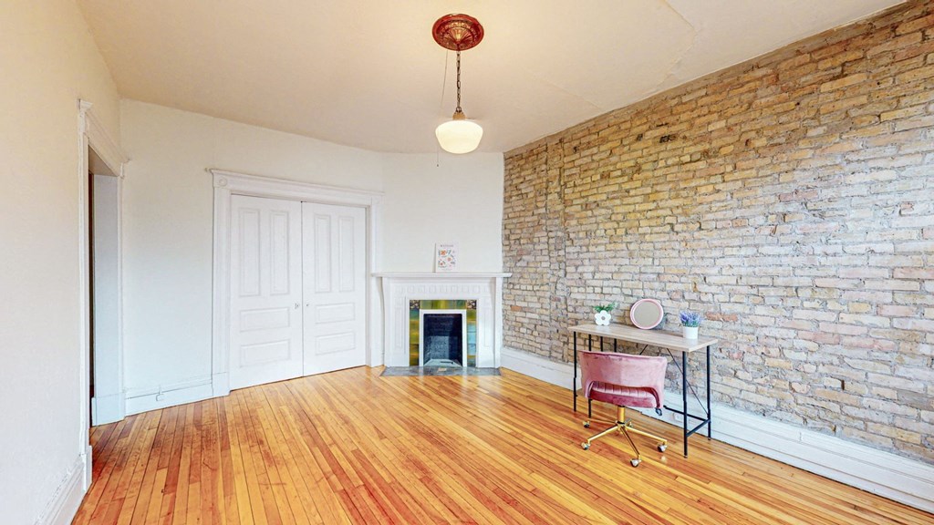 A room with a brick wall and a fireplace.