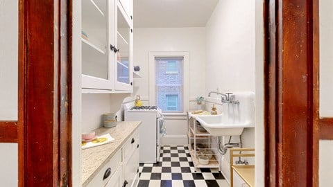 a small kitchen with white cabinets and a black and white checkered floor