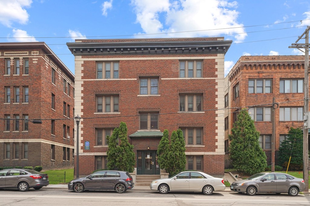 a red brick building with a black awning and cars parked in front of it