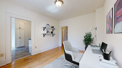 a home office with white walls and hardwood floors