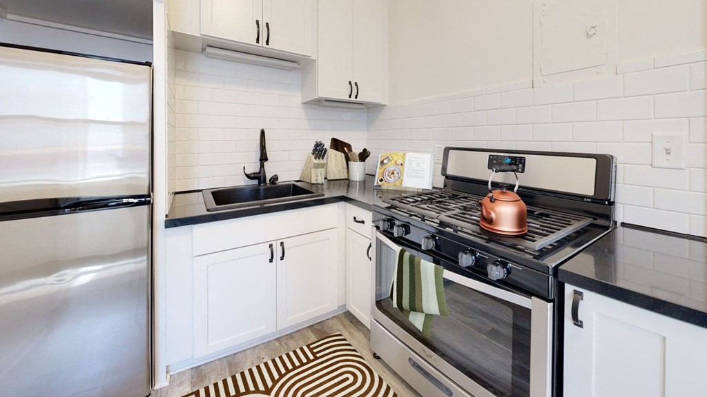 a kitchen with white cabinets and a black and white rug