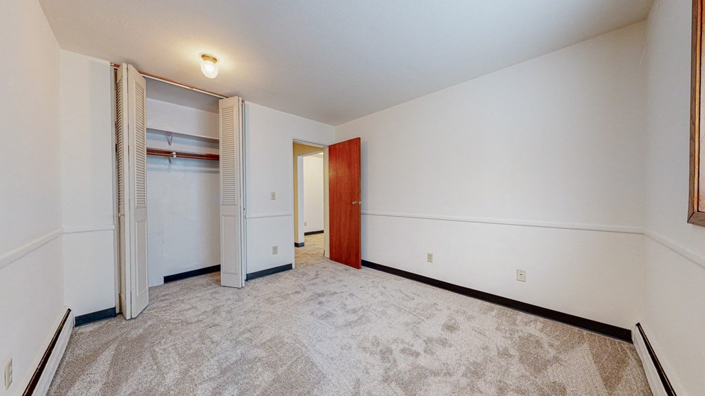 a bedroom with white walls and a closet with a wooden door