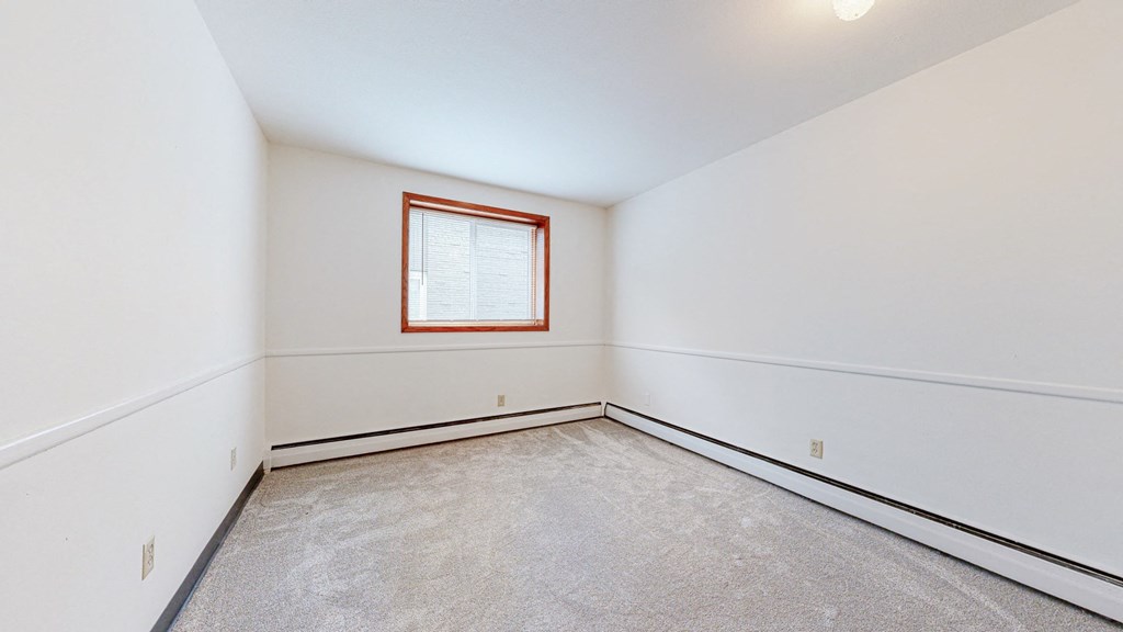 a bedroom with white walls and a window