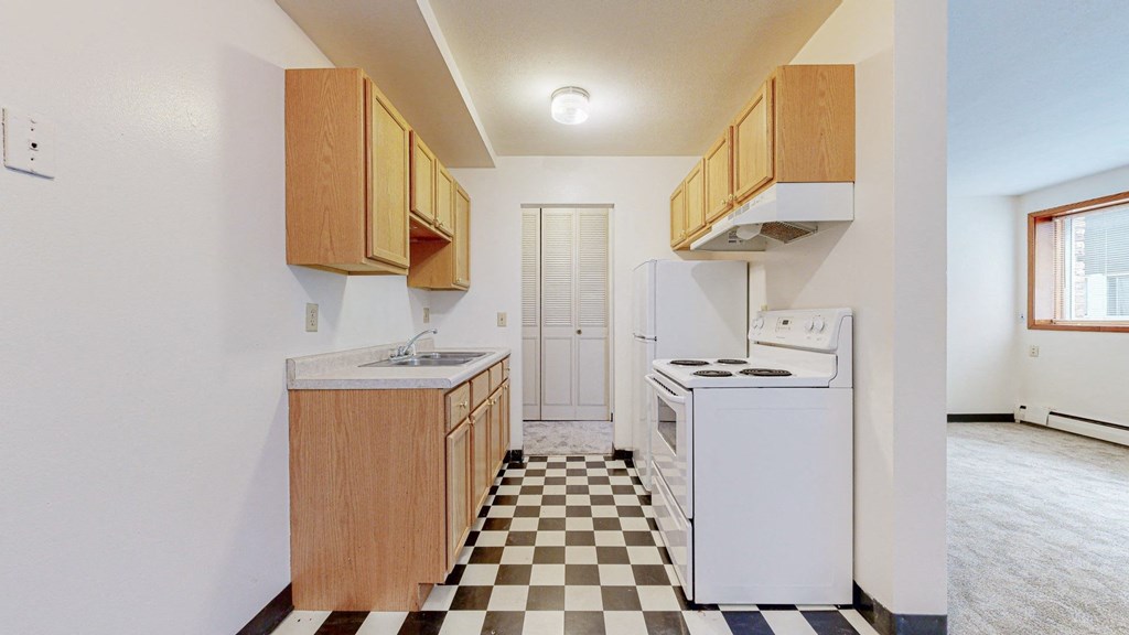 a kitchen with white appliances and a checkered floor