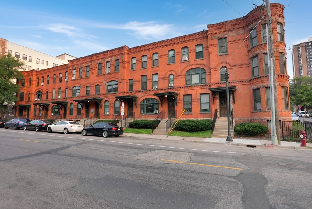 a red brick building on a street corner with cars parked in front of it