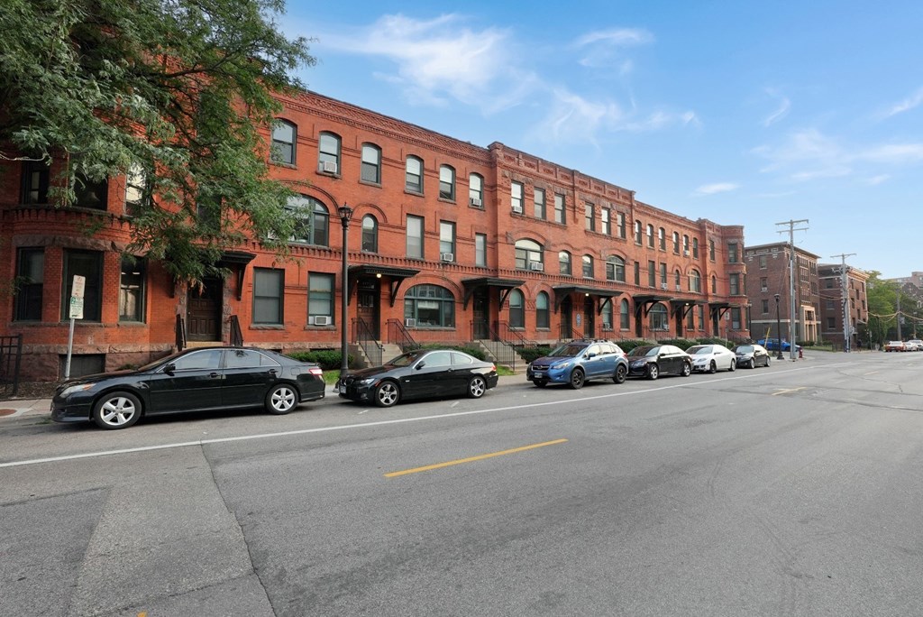 a row of red brick buildings with cars parked in front of them