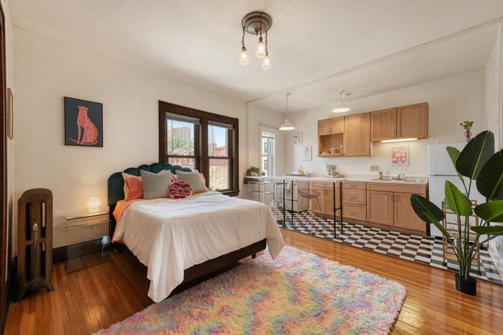 a bedroom with a bed and a kitchen in the background