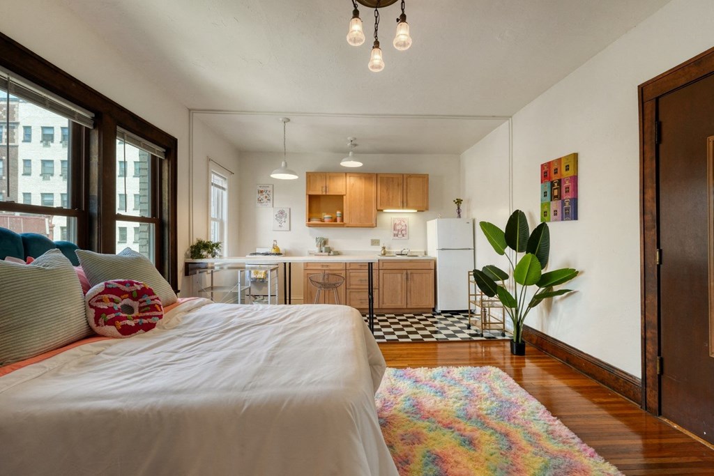 a bedroom with a bed and a kitchen in the background