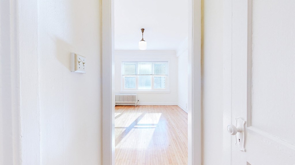 Empty Bedroom with White Walls, Natural Hardwood Flooring, and Wide Windows at The Park Apartments in Minneapolis, MN