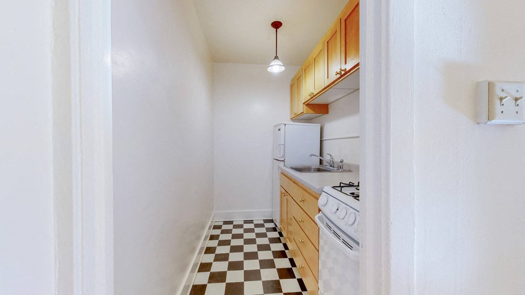 A Cozy Kitchen with Wood Cabinets and Black and White Checkered Flooring at The PArk Apartments in Minneapolis, MN