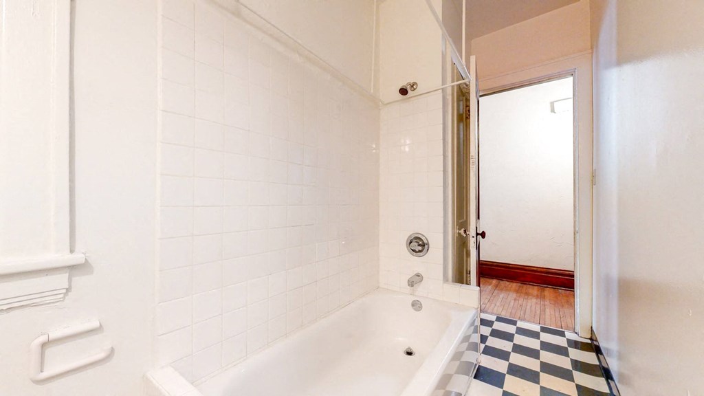 Bathroom with White Tiles and a Black and White Checkered Flooring at The Park Apartments in Minneapolis, MN