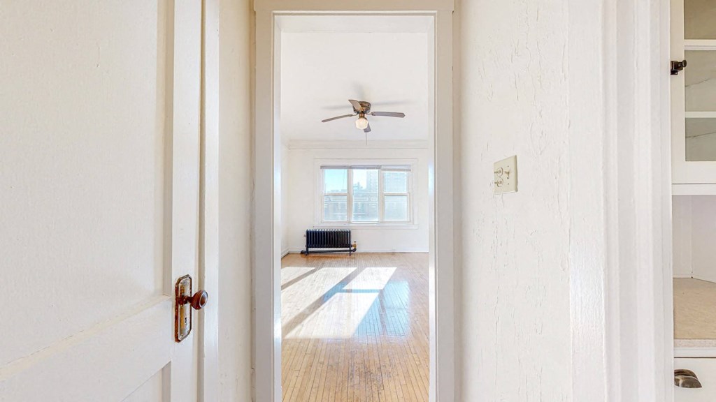 A Spacious Living Room with White Walls, Restored Hardwood Flooring, and a ceiling fan at The Park Apartments in Minneapolis, MN 55403
