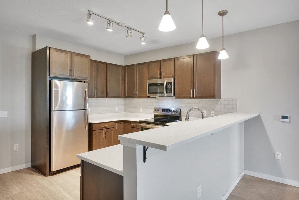 a kitchen with a white counter top and a stainless steel refrigerator
