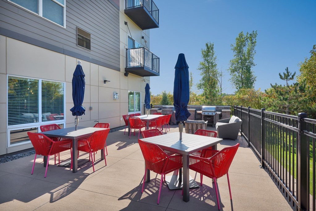 our patio with tables and chairs and umbrellas at our apartments