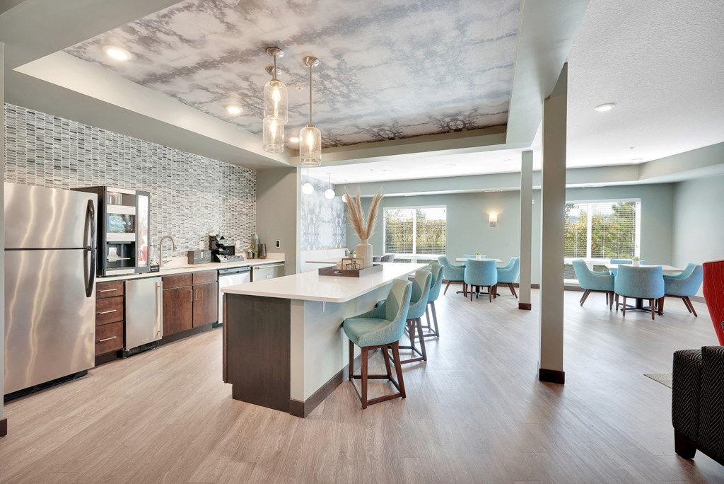a kitchen with a large island and a dining room with blue chairs