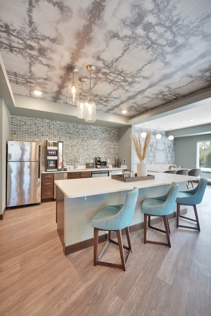 a kitchen with a white counter and blue chairs