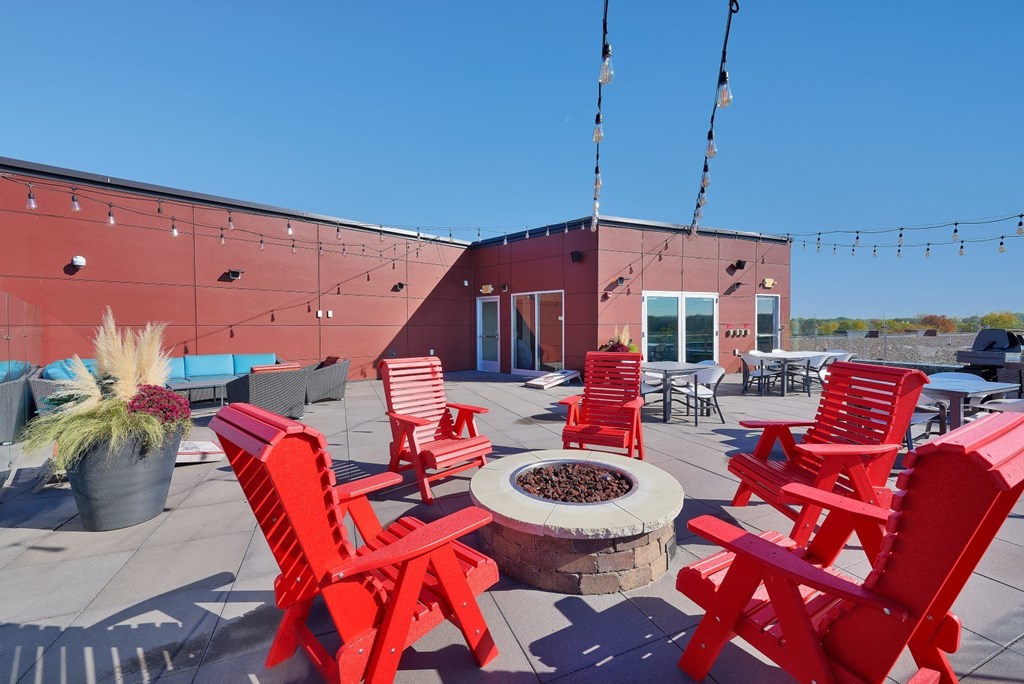 a roof terrace with red chairs and a fire pit