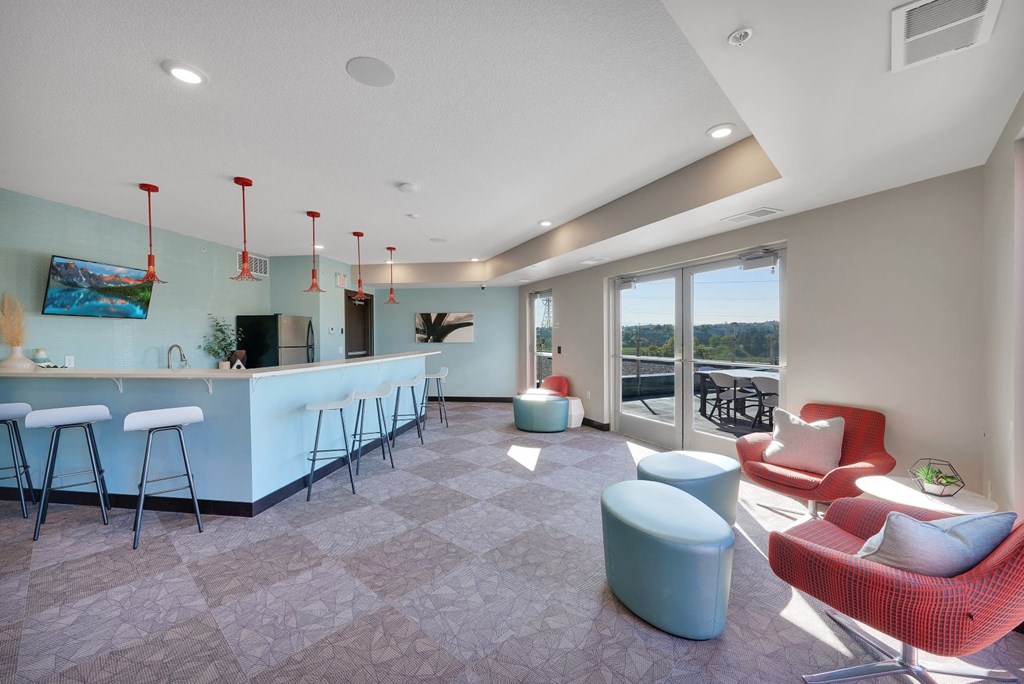 a living room with a kitchen and a bar with chairs