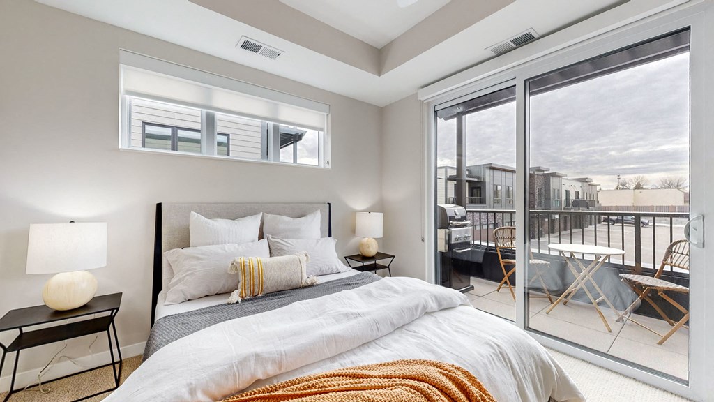 a bedroom with a bed and a sliding glass door to a balcony