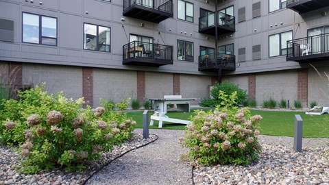 A courtyard with a bench and a small garden with flowers.