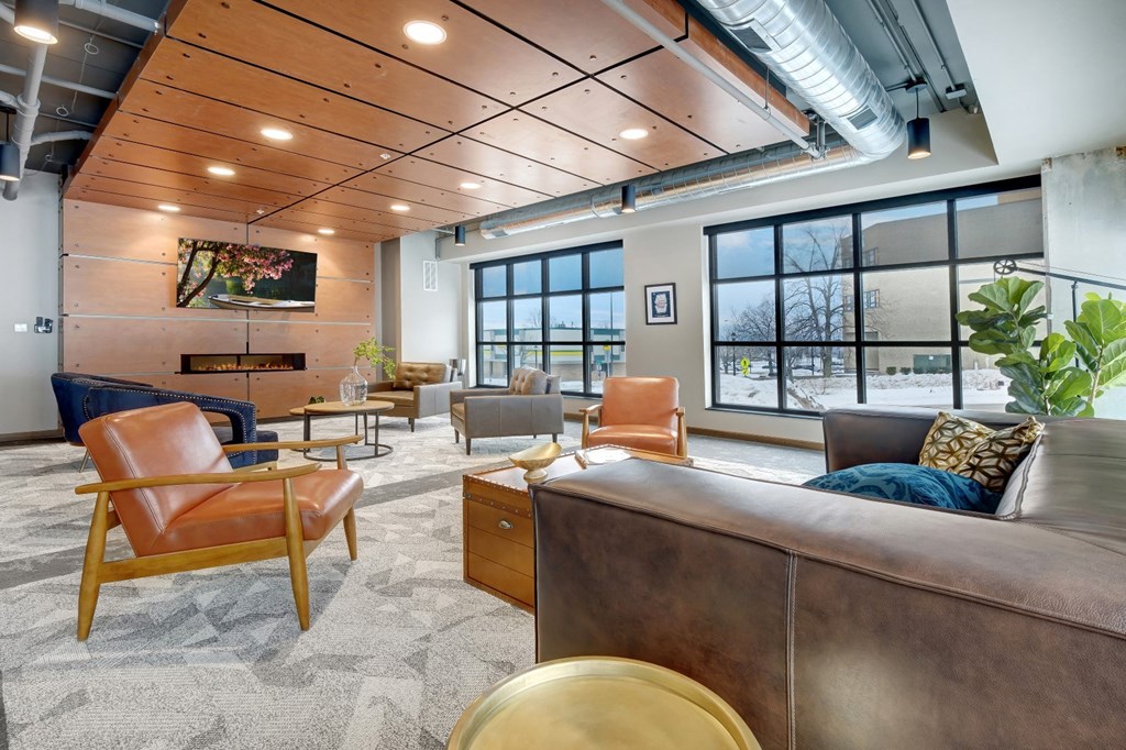 club room with chairs and couches, a fireplace, flat screen tv, and large windows