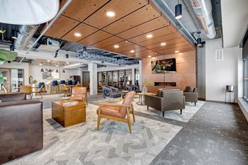 club room with a variety of lounge seating, a fireplace, flat screen tv, high top tables, and a full kitchen