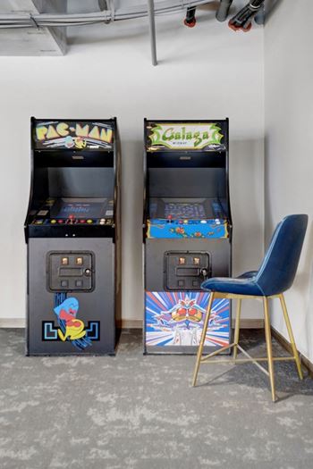 two video game machines in a room with a blue chair