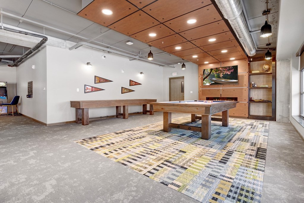 a game room with a shuffle board table, pool table, and a flat screen tv