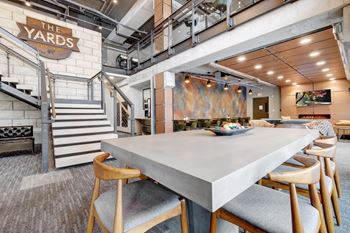 a large table with chairs in a room with a staircase and a sign that says the yards