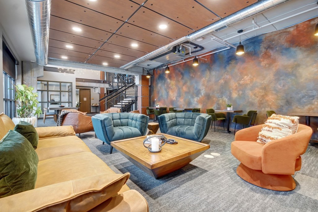 a living room with couches and chairs and a mural on the wall