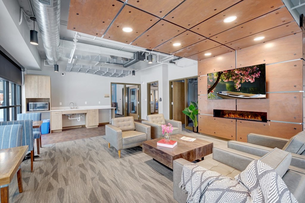 A communcal business center filled with lounge furniture, large windows, and a flat screen tv