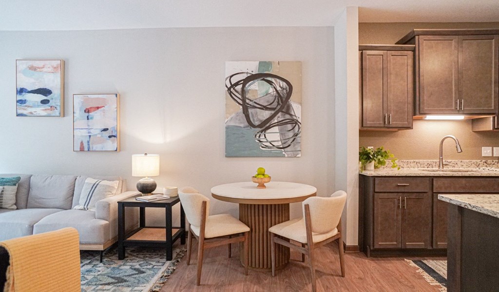 a living room with a table and chairs and a kitchen in the background at The Yards and Backyards, MN 55075