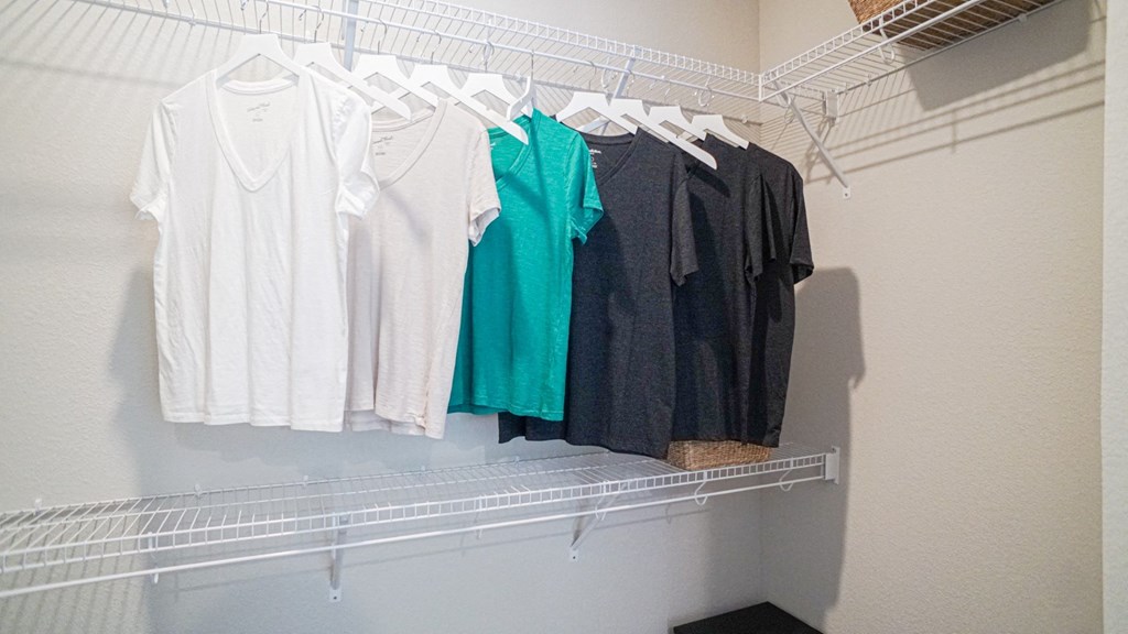 a rack of shirts hanging on a clothes rack in a closet