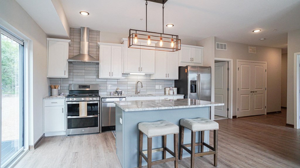 a kitchen with white cabinets and a blue island with three stools