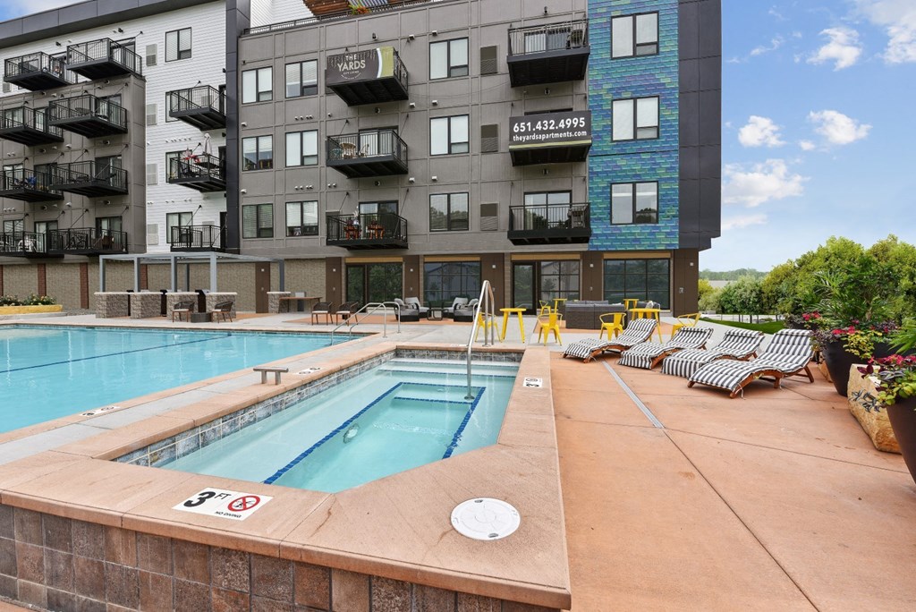 a swimming pool with lounge chairs in front of an apartment building