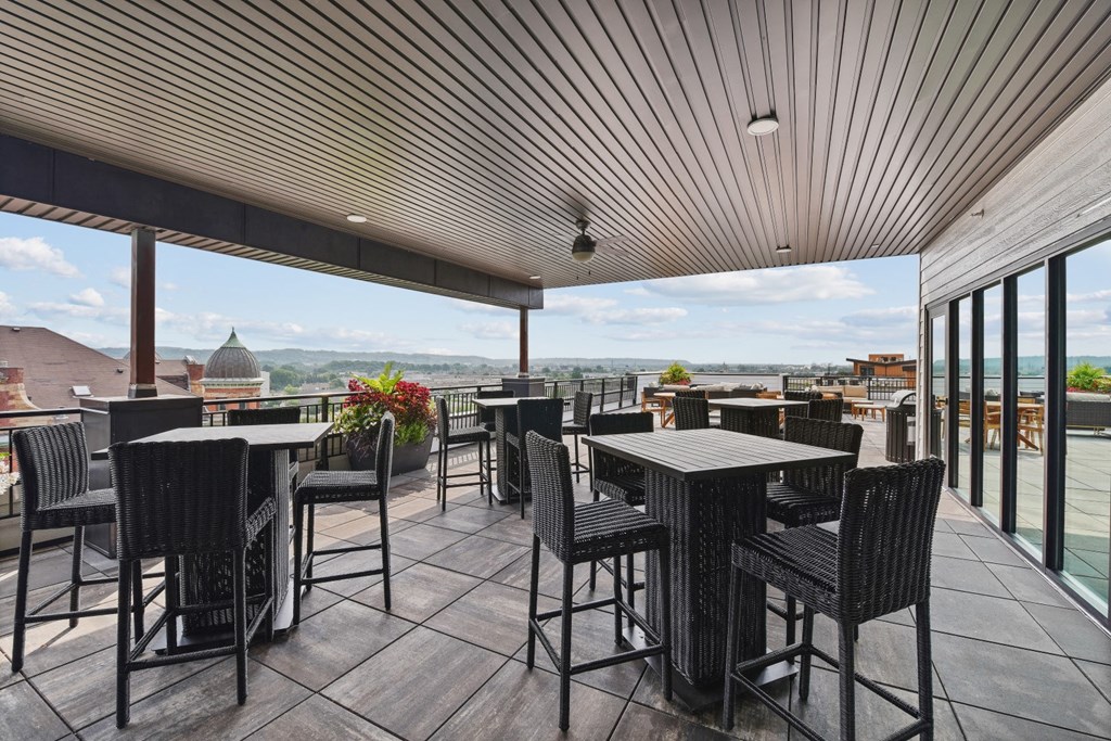a rooftop bar with tables and chairs with a view of the city