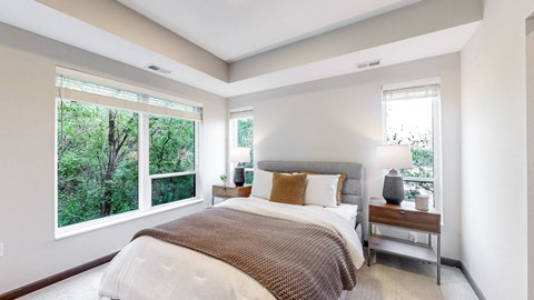 A bedroom with a large bed and a window overlooking a forest.