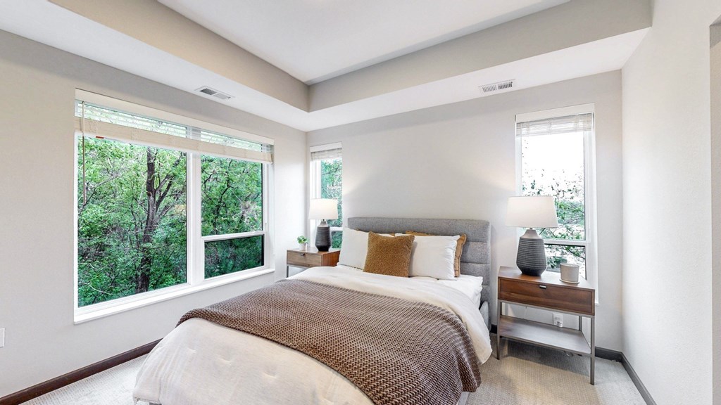 A bedroom with a large bed and a window overlooking a forest.