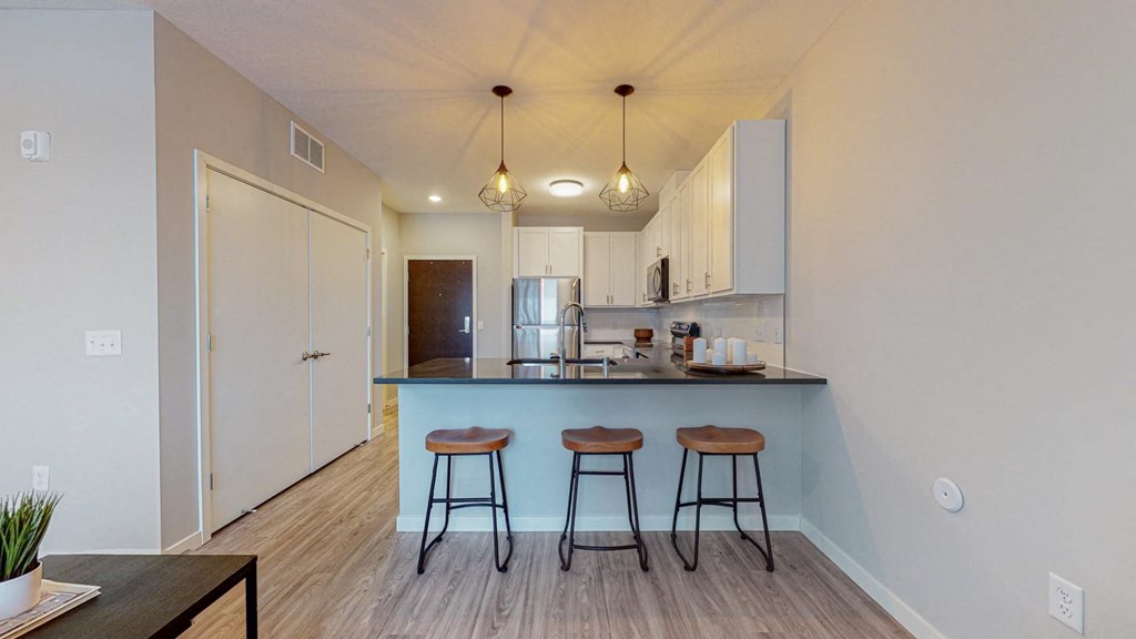 a kitchen with a large island with three stools in front of it at The Morrison, Rosemount Minnesota