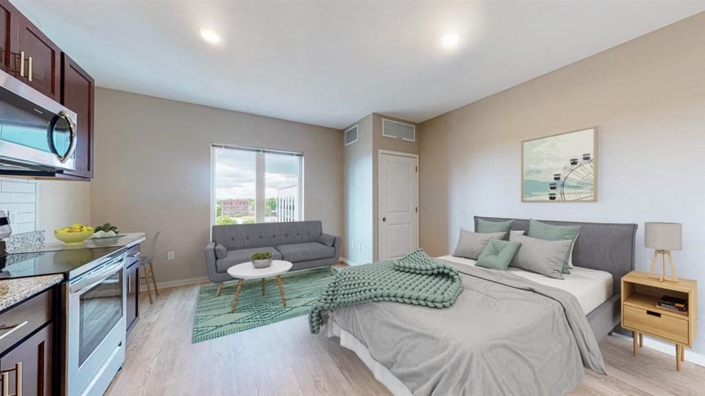 A bedroom with a bed, couch, and a painting on the wall.