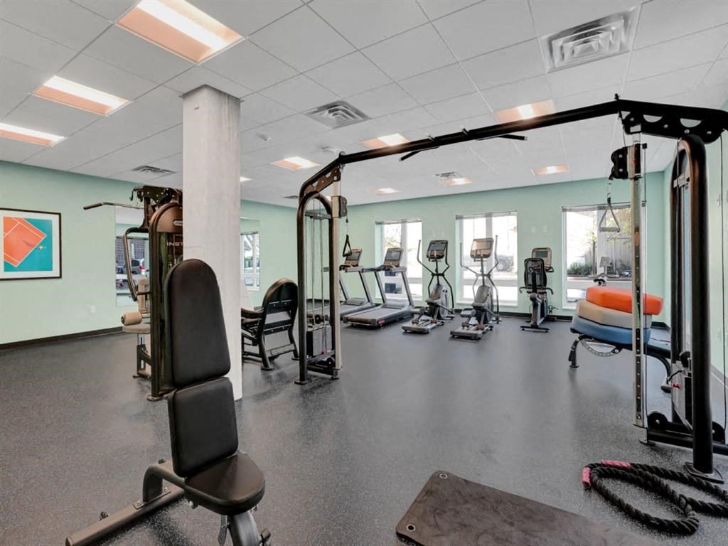 A gym with a variety of equipment including treadmills, weights, and exercise machines.