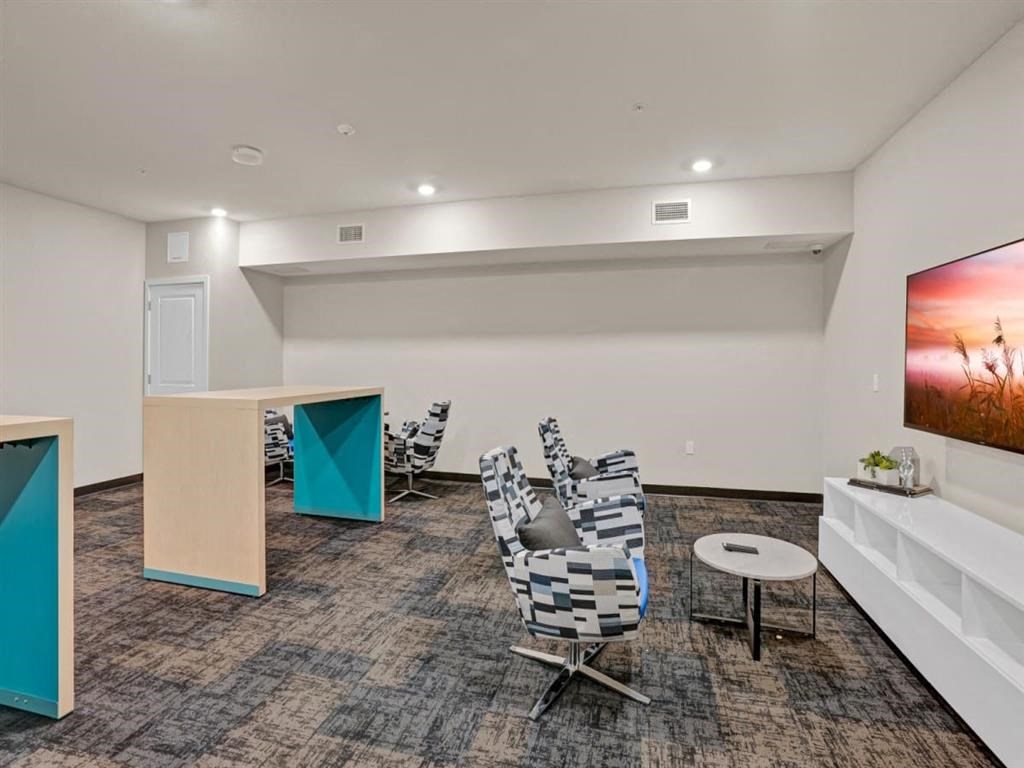 A room with a carpeted floor, a white couch, a TV, and a chair.